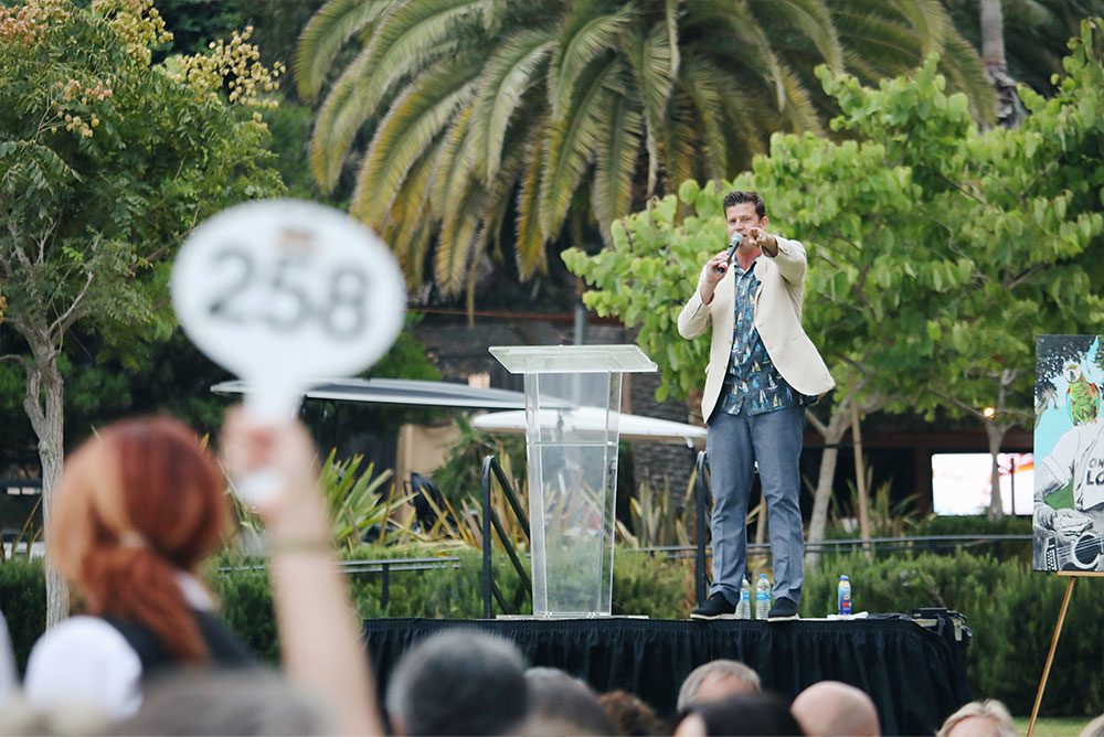 The event's auctioneer on stage (Catalinaville, 2022)